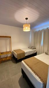 a bedroom with two beds and a chandelier at Casas Carole Maramar Beach House 35 e 36 in Luis Correia +49 photos