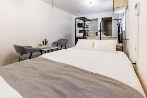 a bedroom with a white bed and a chair at Gran Form Kita 12-jo in Kita-sanjō