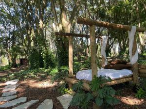 a wooden bed in a forest with trees in the background at SUITE na margem do lago in Hidrolândia +15 photos