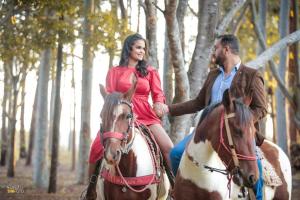 a man and woman riding on horses in the woods at SUITE na margem do lago in Hidrolândia