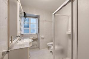 a white bathroom with a toilet and a sink at Casa do jato in Muros