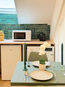 a kitchen with a table with two plates and a microwave at greenhouse home in Corbeil-Essonnes
