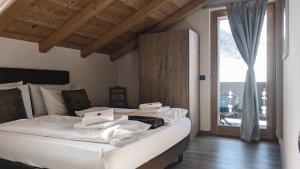 a bedroom with a large white bed and a sliding glass door at Silva: The Alpine Chalet in Livigno