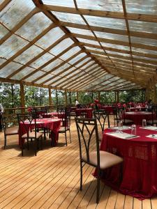 a restaurant with red tables and chairs and a wooden deck at Across The Nile Resort Jinja in Njeru