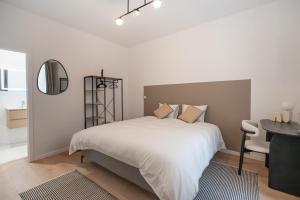 a white bedroom with a bed and a desk and a mirror at Vandenbranden Suites in Brussels