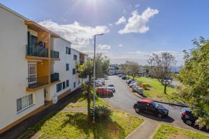 an apartment complex with cars parked in a parking lot at Azorina Lodge in Ponta Delgada