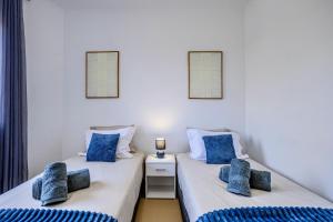 two beds in a room with blue pillows at Azorina Lodge in Ponta Delgada