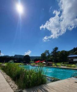 a large swimming pool with the sun in the sky at FeWo Hänsel in Schönwald