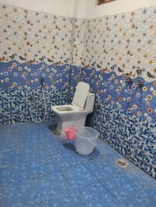 a bathroom with a toilet and a blue tiled wall at Balaji hotel in Badrinath