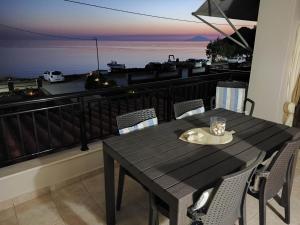 a table and chairs on a balcony with a view of the ocean at liogerma i in Agios Ioannis Kaspaka