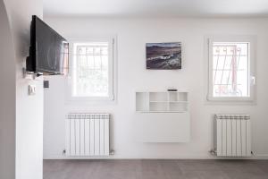 a white room with two windows and a flat screen tv at Piccola dimora Casalecchio vicino al GranReno e Unipol in Zola Predosa