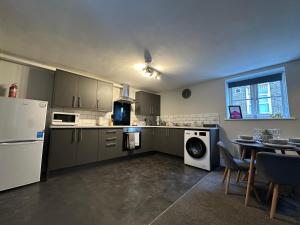 a kitchen with a refrigerator and a table with chairs at Maple House by ShortStays4U A beautiful 2Bedroom House with free parking in town centre! in King's Lynn