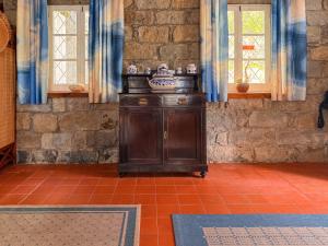 a wooden cabinet in a room with two windows at Entre a Pedra e o Mar in Faial da Terra +54 photos