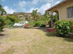 a house with a yard with a car in the background at Mars Place in Saint Georgeʼs