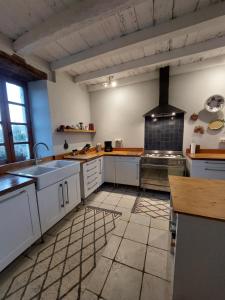 a large kitchen with white cabinets and a sink at La Maison d'ART in Lacour