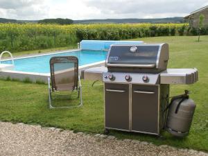 a grill and smoker next to a swimming pool at Cosy vacation home near the sea in Verdun-sur-Meuse