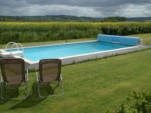 twee stoelen in het gras naast een zwembad bij Cosy vacation home near the sea in Verdun-sur-Meuse