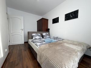 a bedroom with a large bed with white walls and wooden floors at Gustowny apartament in Inowrocław