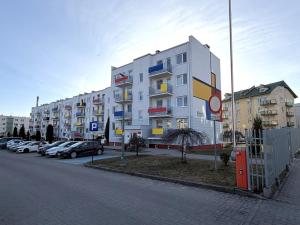 a large white building with cars parked in a parking lot at Gustowny apartament in Inowrocław