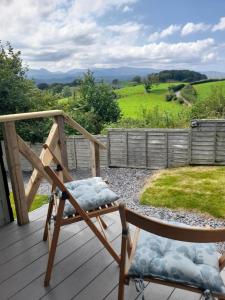 a wooden rocking chair on a deck with a view at Siabod Huts in Betws-y-coed