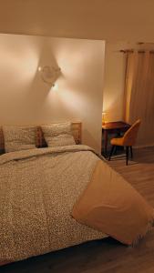 a bedroom with a bed with a table and a chair at L'orée du vignoble in Vaux-en-Beaujolais