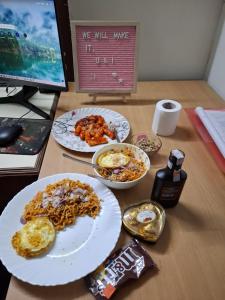 a desk with two plates of food and a computer monitor at Sunya Homestay in Kirāntīchhāp