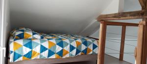 a bunk bed with a colorful comforter on it at La Giraudière avec climatiseur 2 à 4 personnes in Soulgé-sur-ouette