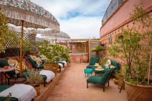 a patio with green chairs and tables and plants at Riad Dar Al Assad in Marrakesh