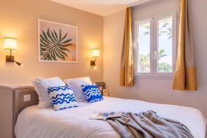 a bedroom with a bed with blue and white pillows at Résidence Pierre & Vacances La Pinède in Hyères +73 photos