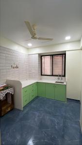 a kitchen with green cabinets and a ceiling fan at the prestige ganga in Solapur