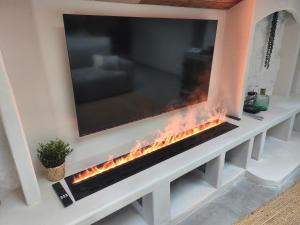 a wall mounted fireplace with a tv on top at Escale à Clisson - Les jardins de Bali in Clisson