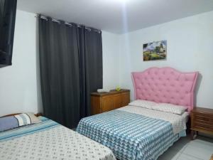 a bedroom with two beds and a pink head board at the silva house in Huacachina