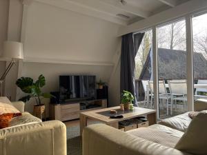 a living room with a couch and a tv and a table at Chalet Séquoia 140, Durbuy nature, piscine,2 chiens Ok in Durbuy