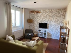 a living room with a couch and a tv on a wall at -La Casa d'Avignon- in Avignon
