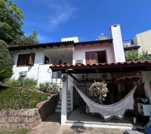 a white house with a porch with a net at Alugo quarto com internet in Porto Alegre