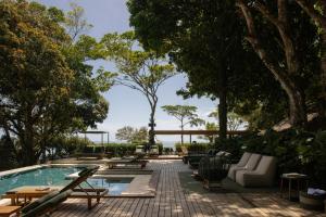 a patio with a pool and tables and chairs at Vila Figo in Trancoso