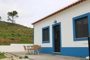 a blue and white house with chairs and a table at Montes da Barca in Aldeia Nova do Concelho