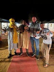 a group of people standing on a red carpet at Merzouga Landscape luxury Camp in Merzouga