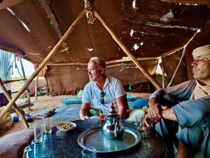 a group of men sitting around a table in a tent at Merzouga Landscape luxury Camp in Merzouga