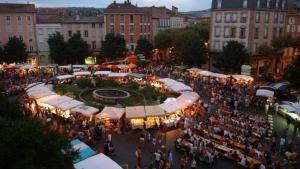 a large crowd of people walking around a market with tents at La Mandarouseraie in Millau