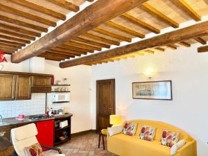 a living room with a yellow couch and a kitchen at Cor Magis in San Quirico dʼOrcia