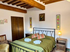 a bedroom with a green bed with two pillows at Cor Magis in San Quirico dʼOrcia
