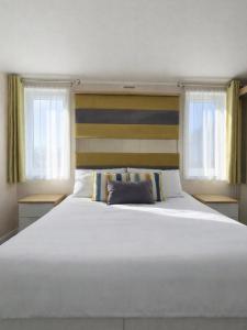 a large white bed in a room with windows at The View Point Northumberland in Newton on the Moor
