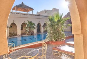 a view of a swimming pool with tables and chairs at kasbah boutique mamouche in Adrouine