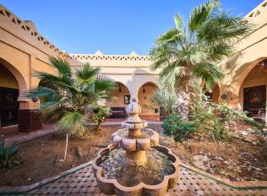 a fountain in the courtyard of a building with palm trees at kasbah boutique mamouche in Adrouine
