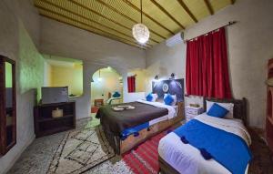 a bedroom with two beds and a television in it at kasbah boutique mamouche in Adrouine
