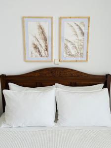 two framed pictures above a bed with white pillows at Villa Di Costa in Nea Skioni