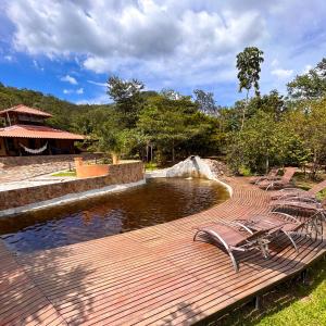 a wooden deck with chairs next to a pond at Pousada Cajuzinho do Cerrado in Cavalcante
