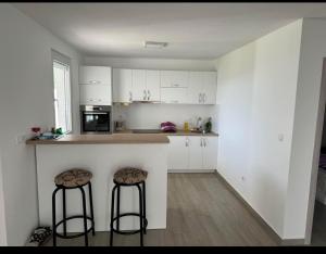 a kitchen with white cabinets and two bar stools at Bela Bar in Pečurice