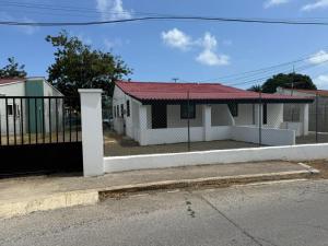 a white house with a red roof and a gate at Island Ease Villa in Willemstad